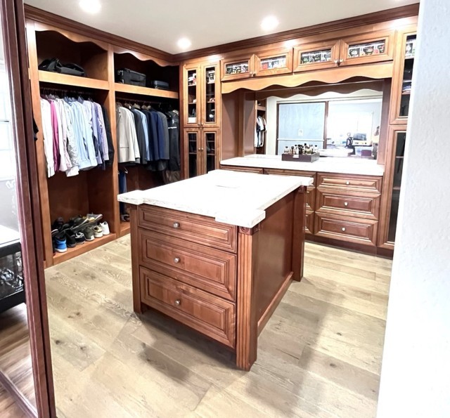 Master closet after organization, featuring neatly arranged clothing, accessories, and shoes in clearly defined zones for easy access and efficient storage.